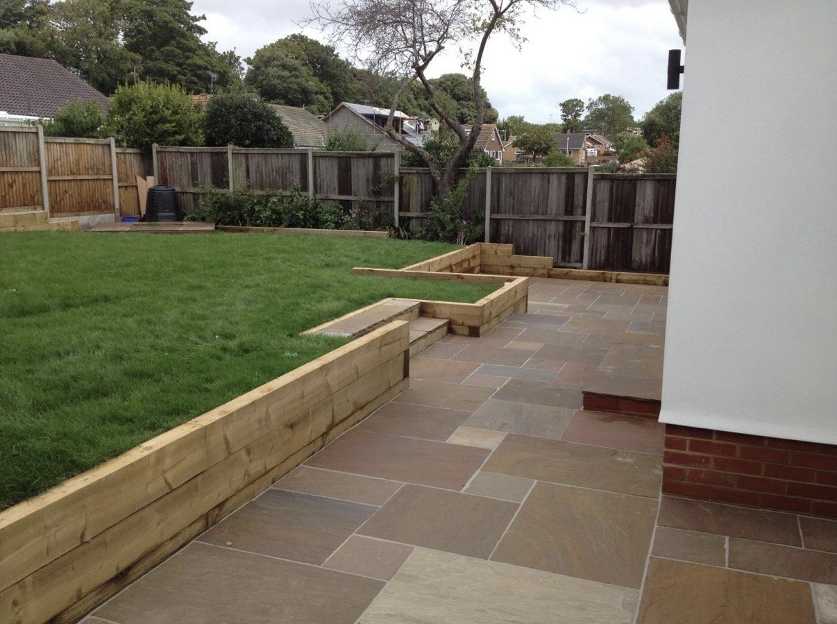 Completed sandstone patio with timber sleeper retaining walls